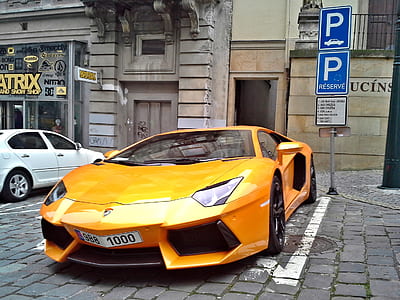 orange sports car parked near building thumbnail