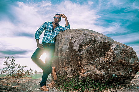 man wearing blue plaid dress shirt beside boulders thumbnail