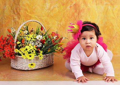 girl sitting beside brown basket with flowers thumbnail