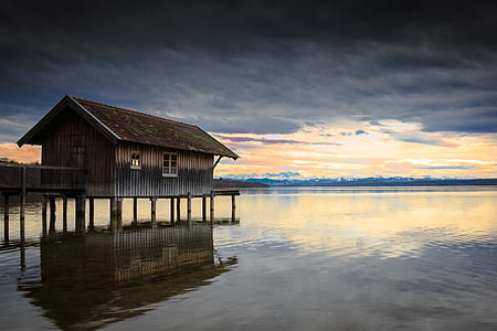 brown wooden house surrounded by body of water thumbnail