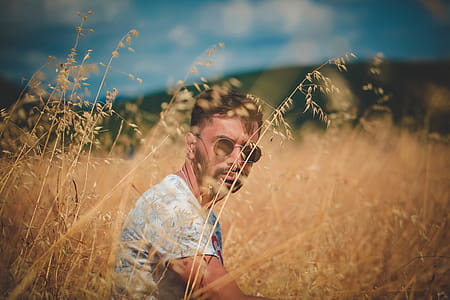 Shallow Focus Photography of Man in Gray Top Sitting on Brown Grass thumbnail