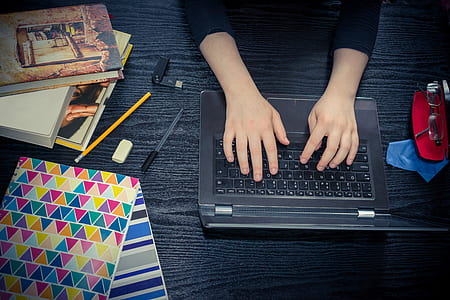 person holding black laptop computer near pencil and pen thumbnail