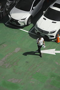 man talking to phone while walking near vehicles thumbnail