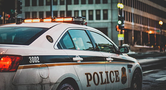 white and black police cruiser on road near building at daytime thumbnail
