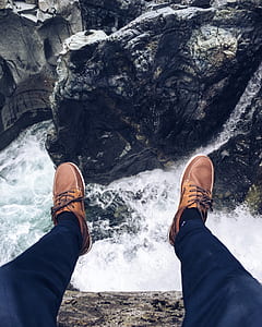 person sitting on mountain near water flowing thumbnail