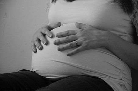 grayscale photo of pregnant woman holding her tummy thumbnail