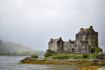 gray concrete house near body of water and mountains thumbnail