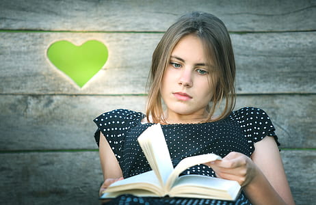 woman wearing white and black polka-dot top reading book thumbnail