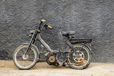 black pedal moped leaning on black wall thumbnail