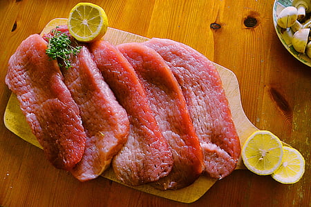 five medium rare meat with lemon on brown wooden chopping board thumbnail