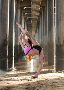 woman stretching her leg under gray concrete bridge during daytime thumbnail