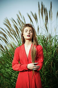 woman in red long-sleeved dress holding green grass on focus photo thumbnail