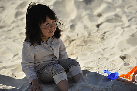 girl in gray sweatshirt sitting while playing sand thumbnail