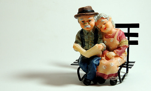 man and woman figurines sitting on black wooden bench thumbnail