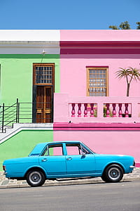 blue sedan beside green and pink house thumbnail