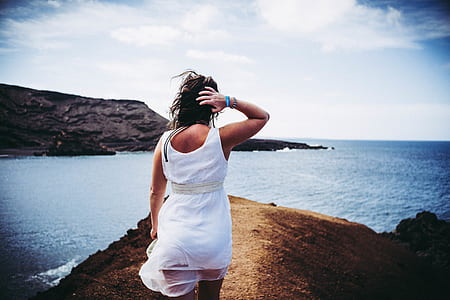 Woman Wearing White Sleeveless Mini Dress on Top of Brown Sand Near Body of Water thumbnail