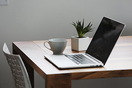 flip-on gray laptop computer near white ceramic teacup on brown table thumbnail