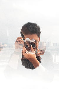 surrealism photography of man using black and gray Canon DSLR camera thumbnail