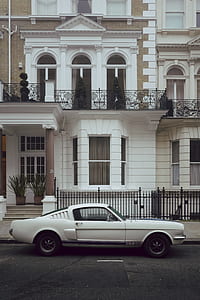 classic white Ford Mustang Fastback GT350 parked near white concrete building during daytime thumbnail