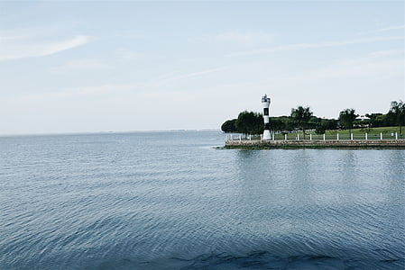 white and black lighthouse near body of water thumbnail