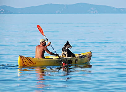 man and dog riding on boat during daytime thumbnail