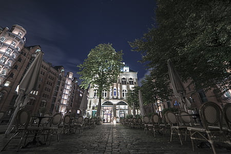 empty chairs by buildings under tree during nighttime thumbnail