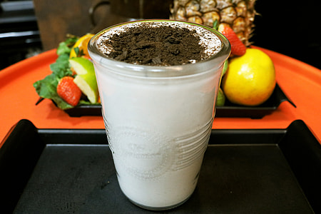 clear drinking glass filled with white liquid with black powder toppings thumbnail