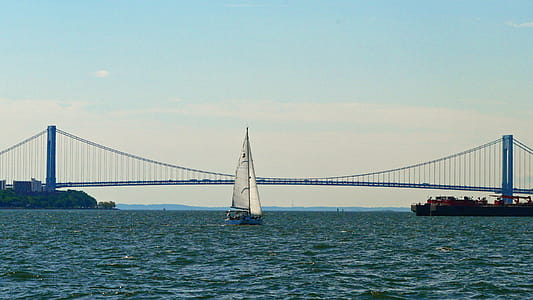 A sailboat on the waters of New York Harbor sails toward the Verrazon-Narrows Bridge and the open waters of the Atlantic Ocean. thumbnail