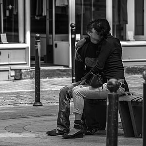 grayscale photo man and woman kissing while sitting on chair thumbnail