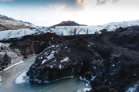 person standing on top or rock formation beside body of water thumbnail
