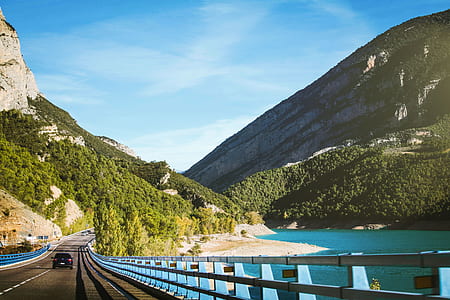 black vehicle crossing road near mountains at daytime thumbnail
