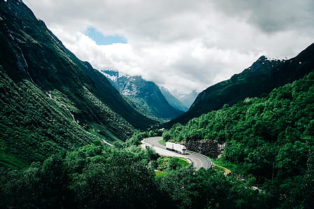 photo of white freight truck along paved road in the mountain thumbnail