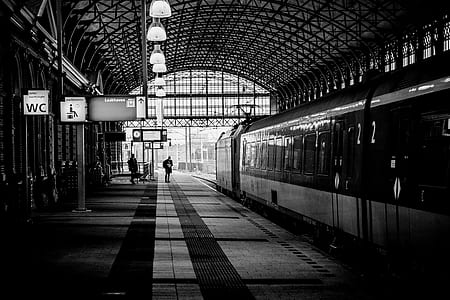 grayscale photography of two person standing on train station thumbnail