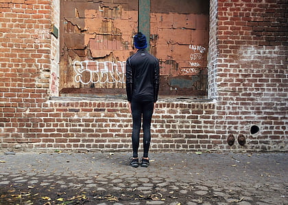 person standing in front of brown wall bricks thumbnail