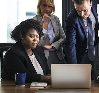 two women and man looking at brown laptop computer thumbnail