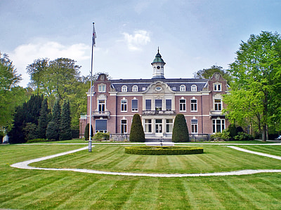 red, white, and gray concrete building with flagpole on lawn thumbnail