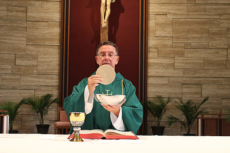 priest holding ostia and bowl during on altar thumbnail