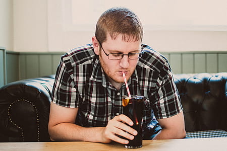 Man Sipping Drink From Clear Glass thumbnail