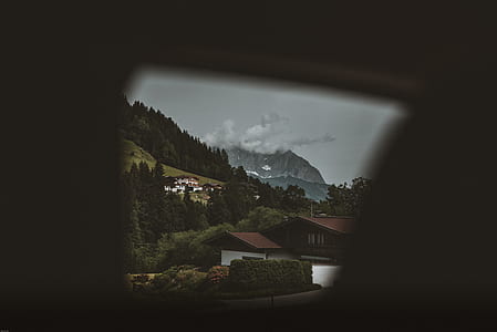 brown and white house beside trees across mountain under white cloudy skies thumbnail