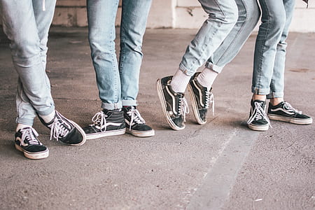 four people wearing blue jeans and black-and-white Vans Old Skool shoes thumbnail