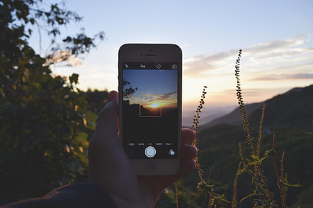 person holding capturing golden hour using iPhone thumbnail