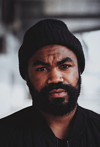 selective focus photography of man wearing bomber jacket and black knit cap thumbnail