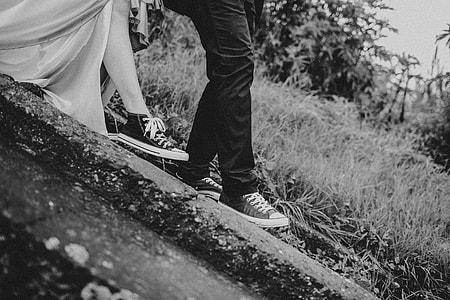 grayscale photo of man and woman walking near grass thumbnail