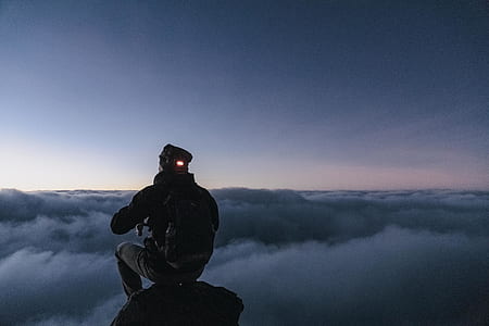 man sitting on rock while looking at sea of clouds thumbnail