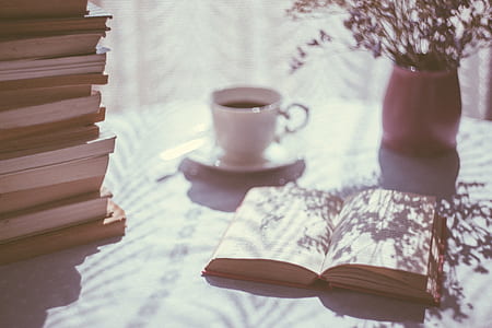 open book beside white ceramic mug and pink ceramic vase on top of table thumbnail