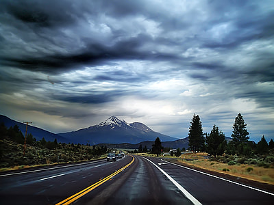Highway Road into the mountains under heavy clouds thumbnail