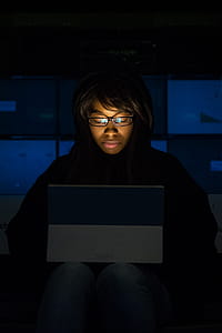 Woman Wearing Eyeglasses Looking at Tablet Computer in Dark Room thumbnail