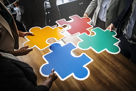 four persons holding yellow, red, green, and blue puzzles thumbnail