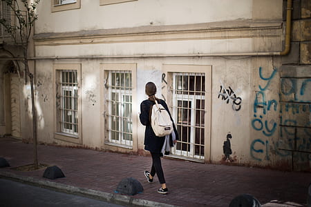 woman walking beside concrete building thumbnail