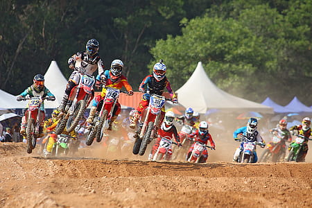men riding motocross dirt bikes near green leafed trees thumbnail